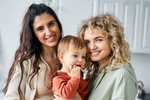 two mums smiling at the camera with a toddler for rainbow fertility